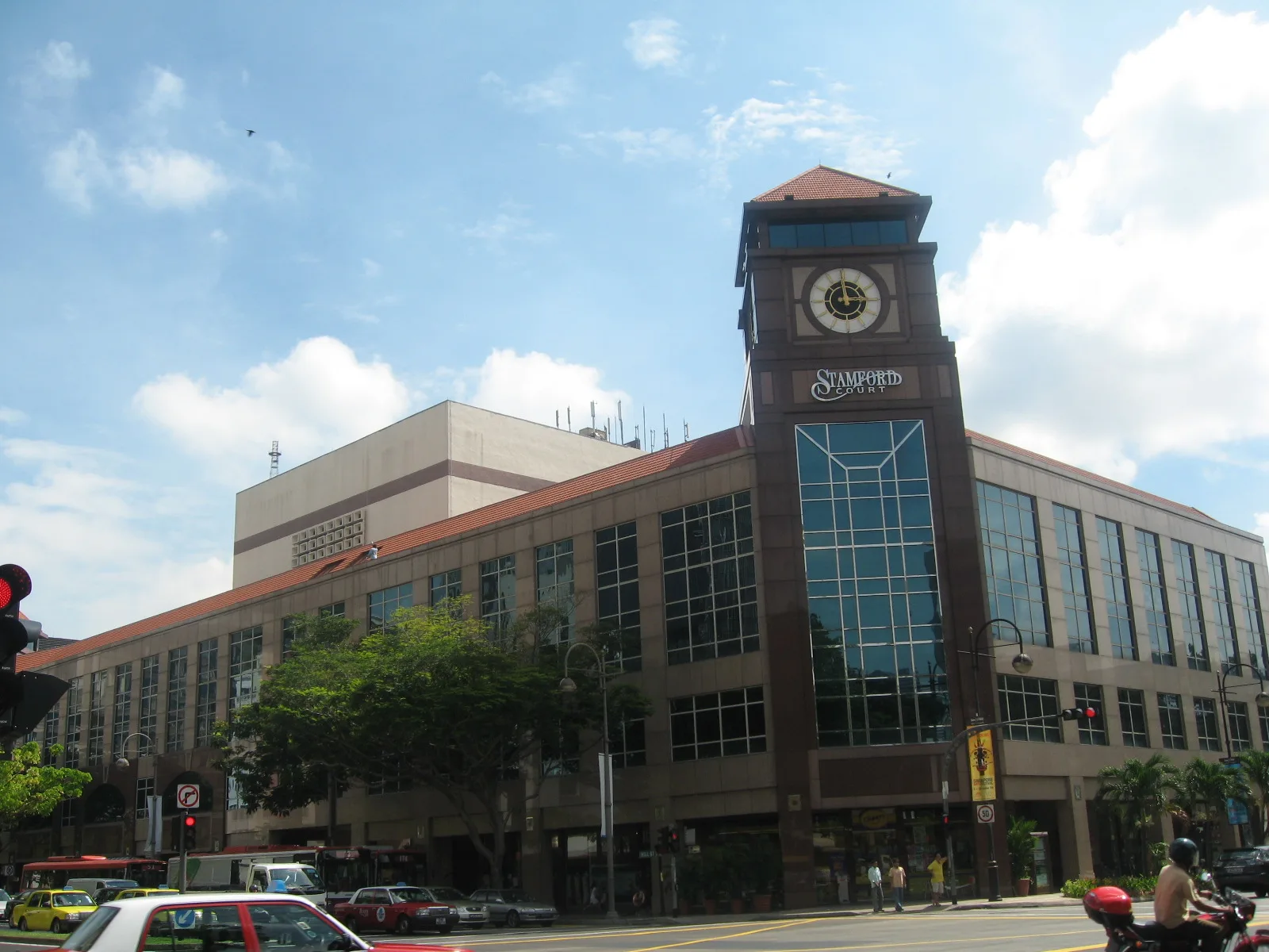 Stamford Court in June 2006, with its original dark granite facade and clock tower. Photo: Terence Ong, CC BY 2.5, via Wikimedia Commons (resized).